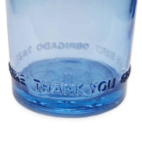 Bližnji pogled na reliefni odtis besede  Thank You na spodnjemrobu modre steklenice OmWater.