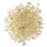 Kupček drobnih, svetlih in prosojnih koščkov naravnega kadila damar na beli površini.
